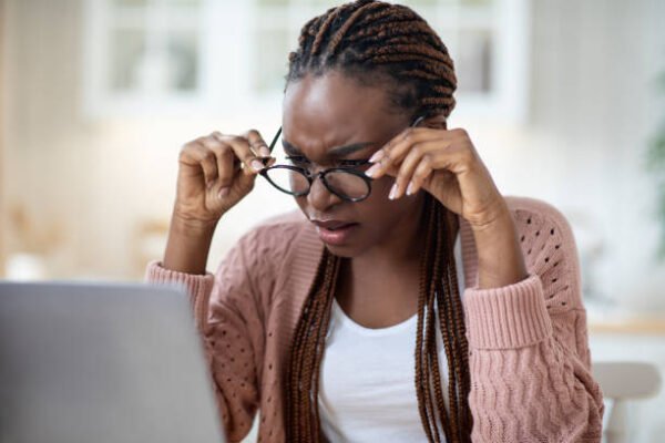 Eyesight Problems. Black Lady In Glasses Squinting While Looking At Laptop Screen, Millennial Freelancer Lady Having Eye Vision Troubles While Working Remotely With Computer At Home, Closeup